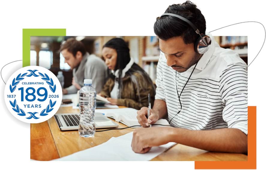 Students studying at a desk with notebooks and laptops in a focused learning environment