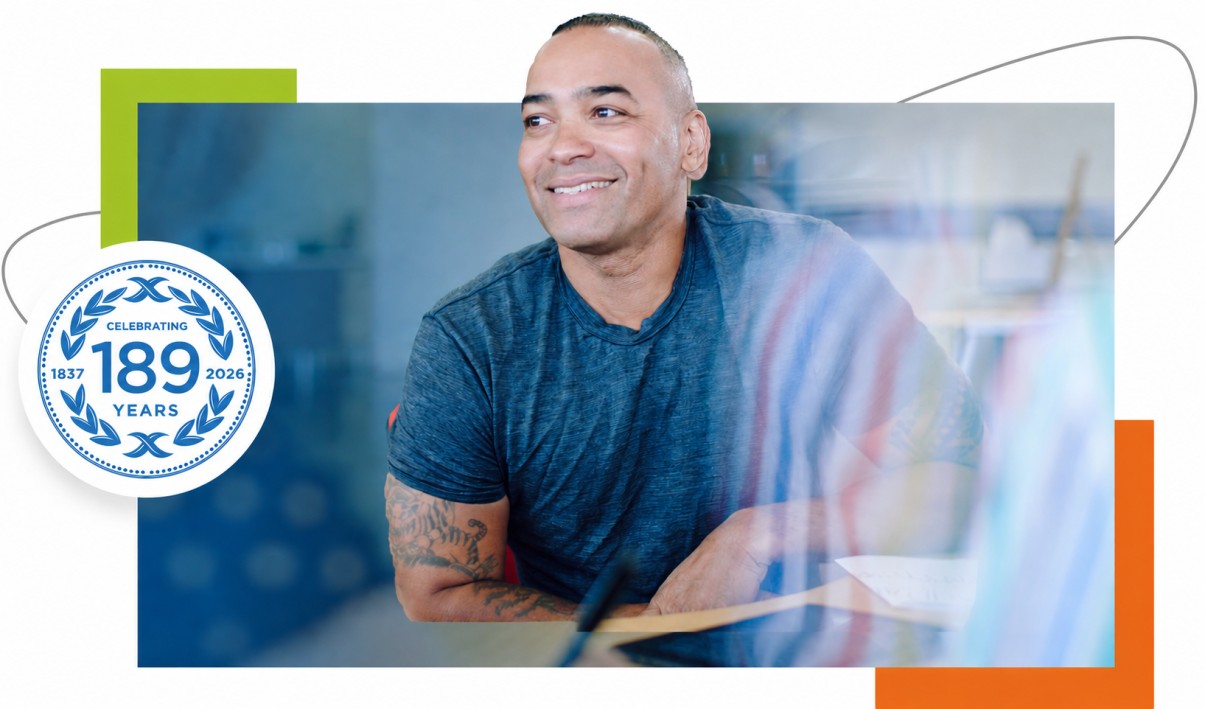 Smiling man in a professional office setting with a Celebrating 189 Years anniversary badge showing 1837–2026 on a corporate banner design.