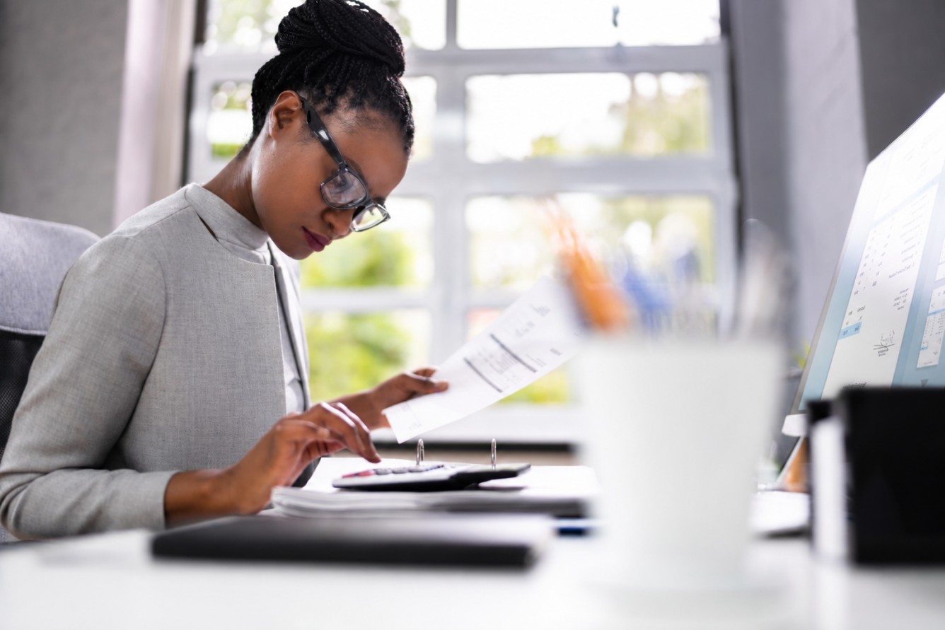 Accounting professional reviewing an invoice and using a calculator, representing the AAT Level 4 Diploma for Professional Accounting Technicians