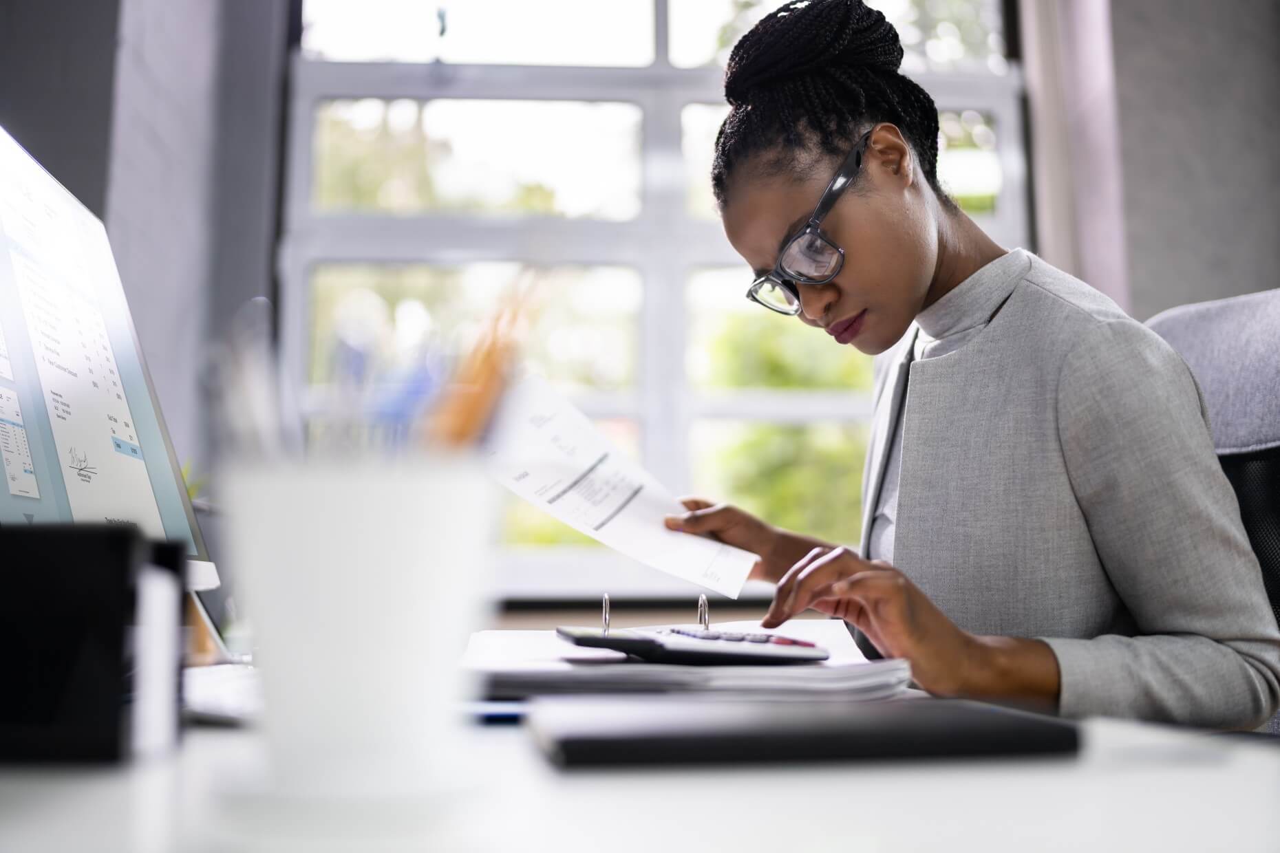 Accounting professional reviewing an invoice and using a calculator, representing the AAT Level 4 Diploma for Professional Accounting Technicians