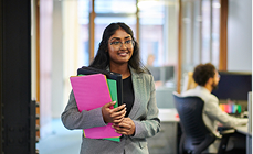 Office administrator holding colourful folders in a bright modern office Office administrator holding colourful folders in a bright modern office
