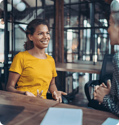 Woman in a yellow top talking to an adviser about her ReAct+ funding eligibility