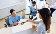 Smiling woman planning a new business with colourful sticky notes on a glass wall Medical receptionist in scrubs helping a patient at a clinic reception desk